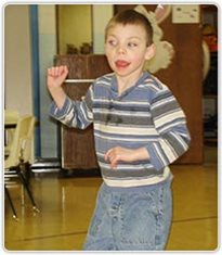 A young boy dancing in a classroom.
