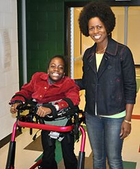 A young girl in a Rifton Pacer gait trainer posing with her mom.