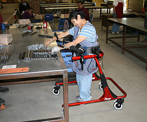 Movement disorders don’t stop this woman from assembling parts in a warehouse space in a Rifton gait trainer