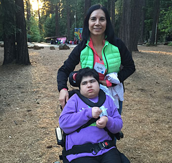 A mom assists her daughter in a wheelchair as they take in the forest air at an inclusive camp