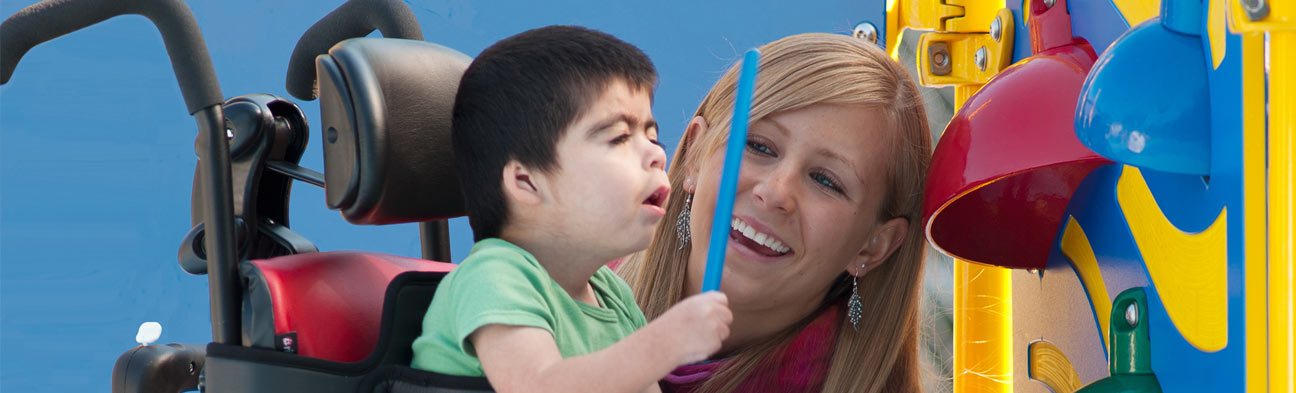 A boy sits in a Rifton Activity Chair and plays with his caretaker.