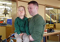 A father holds his young daughter who has spinal muscular atrophy.