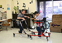 Two adults in gait trainers dance, in a MOVE International facility with musical notes on the wall