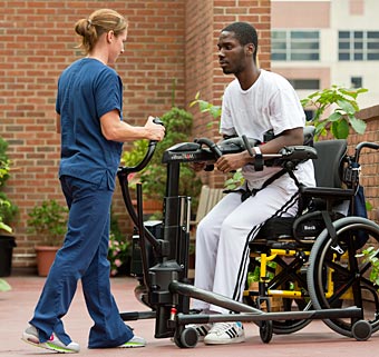 A therapist uses a Tram as a patient transfer technique to safely transfer a young man from sit to stand.