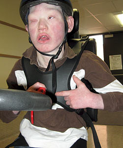 A young boy with muscle control issues sits upright in his adaptive tricycle thanks to a Rifton chest prompt support system.