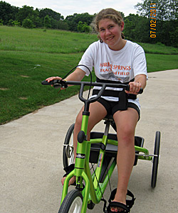 Brooke Slabaugh is all smiles as she ride her special need trike over a paved surface