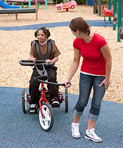 A young girl helping a special needs child on a tricycle during Bike 4 Friendship