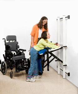 A therapist helps a young girl in a wheelchair transfer to a disabled changing table for toileting