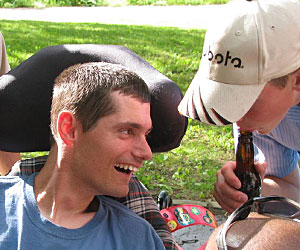 Duane outside amongst friends, looks over in amusement to a young boy as he makes a sound with a bottle 