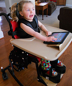 A young girl with special needs is actively playing on an ipad while sitting in the Rifton Activity Chair