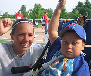 Jen Burke and Scott Conlon, a young boy with ROHHAD Syndrome both fist pump at an outdoor event