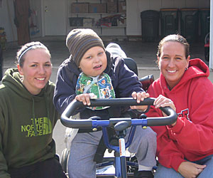 Scott Conlon, a young boy with ROHHAD Syndrome, takes a ride on his Rifton tricycle with two pals