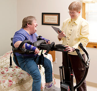 A therapist practices safe patient lifting by transferring a woman from a treatment table using the Rifton TRAM