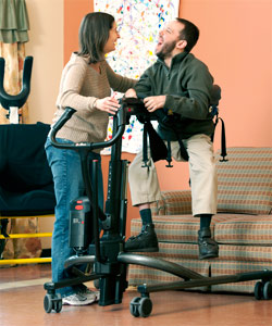 A physical therapist uses the Rifton TRAM to lift a patient from sitting to standing with this new mobility device