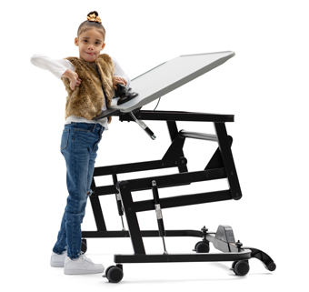 A girl stands at a Rifton Adaptive Desk and grips a grab bar on its surface.