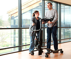 Two therapists help a young girl walk in the TRAM during a mobility product demo