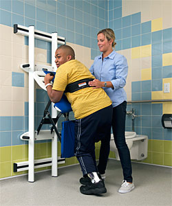 A therapist helps a young boy onto a Rifton support station to help with his changing needs