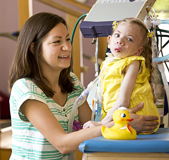 A young girl with special needs and her caregiver.