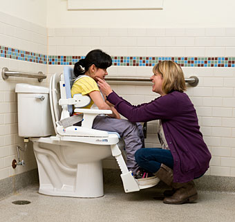 A caregiver smiles at a young child using the prompts on the Rifton HTS to help improve her toileting training experience.