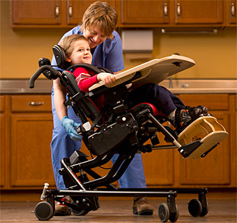 A therapist uses the tilt-in-space feature on the adaptive positioning chair for a young child with cerebral palsy. 
