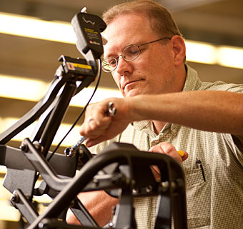 Tightening a bolt on the Rifton TRAM, a Rifton worker focuses on quality control for the adaptive equipment
