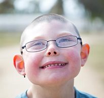 A young boy with disabilities looks up at the sky with a big smile