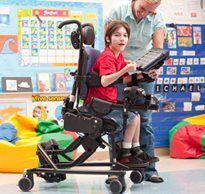 A therapist is teaching a special needs student active sitting and positioning in a Rifton Activity Chair in a classroom setting