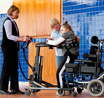 A special education teacher uses a Rifton TRAM to safely get a patient from sitting to standing