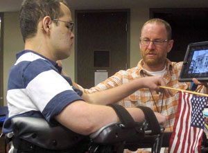 A TBI patient goes from sitting to raise his flag and pledge allegiance.