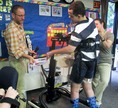 A TBI patient surrounded by his teacher and classmates goes from sit to stand to walking in his TRAM.