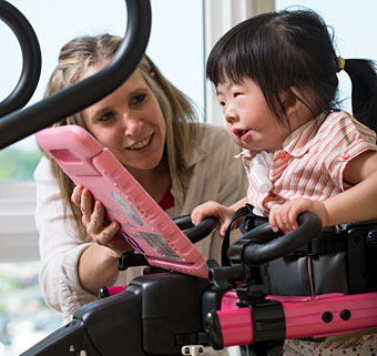 A young girl practices gait training on a treadmill using a Rifton Dynamic Pacer while being assisted by a therapist
