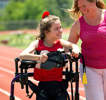 A young girl in a Pacer gait trainer with her arms positioned incorrectly out to the sides.