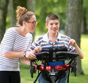 A therapist assisting a child with special needs in a Rifton Pacer gait trainer.