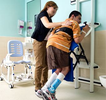 A teacher assist a student with special needs who is actively participating in toileting motor skills development