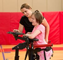 A therapist helps properly position a child in a Rifton Pacer gait trainer using a checklist