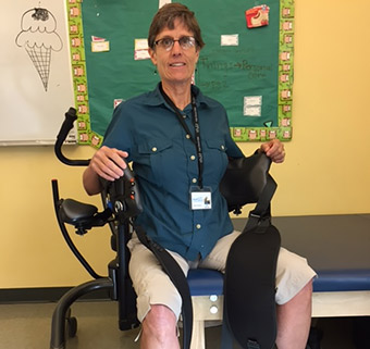 Jill Barrett sitting in a TRAM, demonstrating a transfer to the Rifton Adaptive Tricycle.