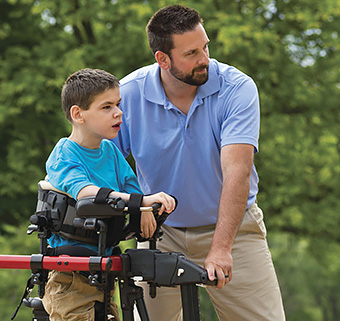 A teacher outside the classroom works with a student on functional mobility using a gait training device