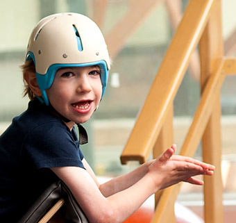 A boy standing in a Prone Stander and smiling.
