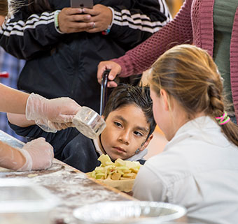 A young boy watches his apple pie being made at Rifton's birthday party.
