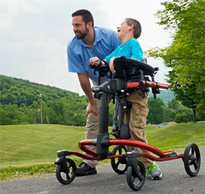 A therapist guides a boy with cerebral palsy outside in a gait trainer using task-specific activities to help him increase his gait speed 