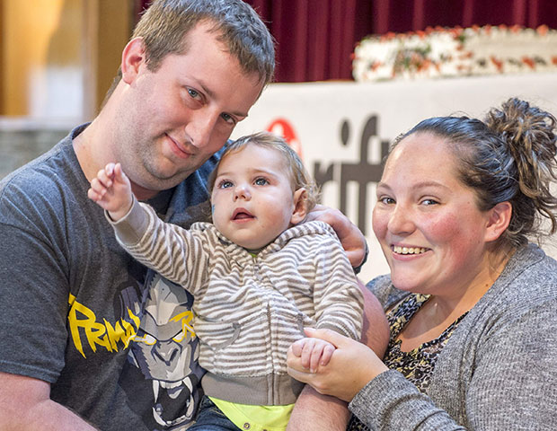A mom and dad with their child smile while attending as friends at Rifton Equipment's birthday party.