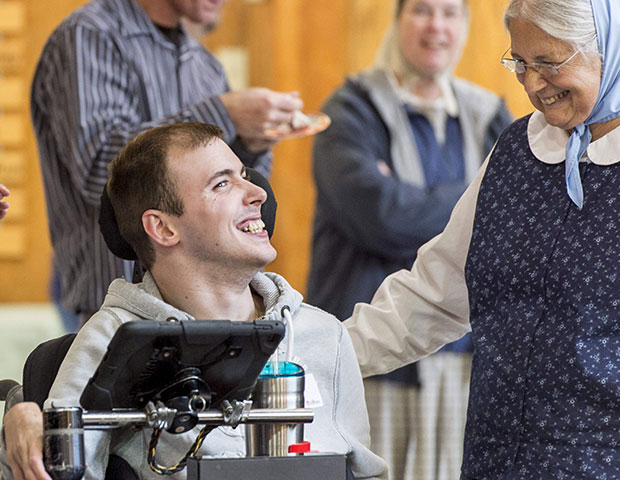 An elderly woman speaks to a guest at rifton equipment's birthday celebration.