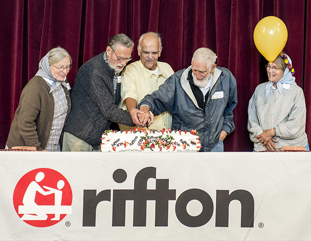 Five elderly people assist in the cake cutting ceremony at rifton's birthday party.