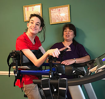 A client uses the Rifton Pacer to walk on a treadmill.