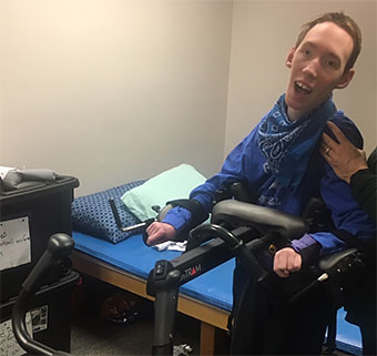 A young client standing and walking with his physical therapist with the aid of a Rifton TRAM.