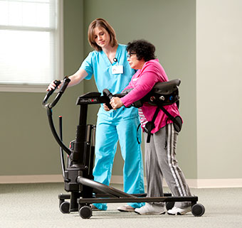 A therapist helps a patient with brain injury in an early mobilization exercise in the ICU.