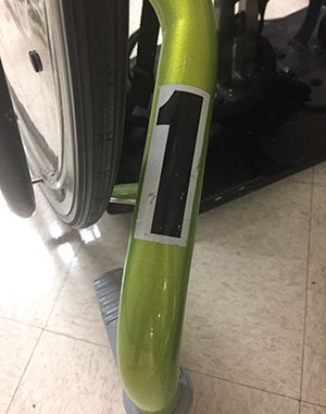 A close up of a number placed on a green dynamic stander as an organizational tactic for adaptive equipment at the Langan School.