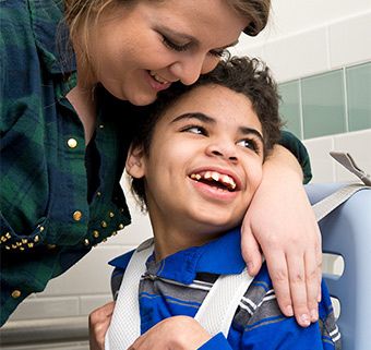 A boy sitting in the Rifton HTS with a caretaker by his side