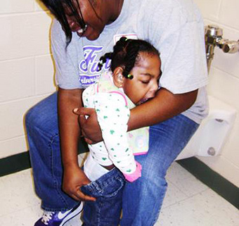 A small child standing during toileting in the home