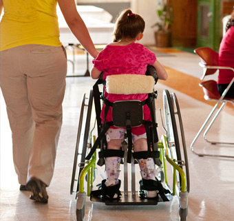 A little girl walking down a hallway in a Rifton Mobile Stander